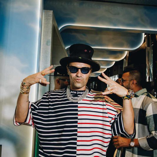 Alec Monopoly wearing sunglasses and striped shirt.