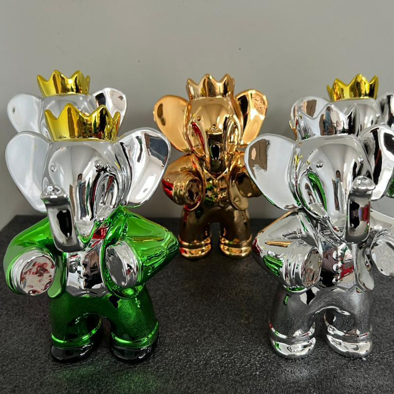 Set of chrome Babolex elephant sculptures in silver, green, and gold, each wearing a crown and suit