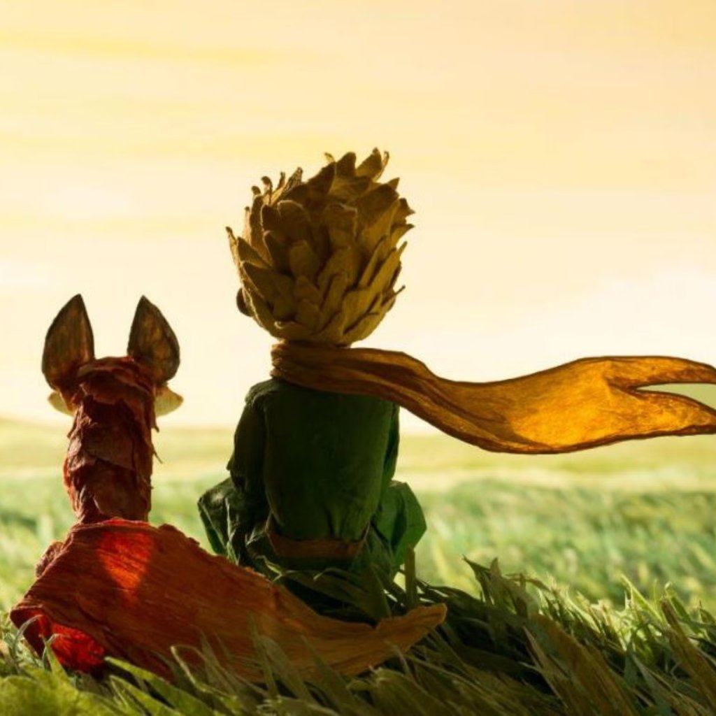 the Little Prince sitting with the Fox in a grassy field, with a sunset in the background