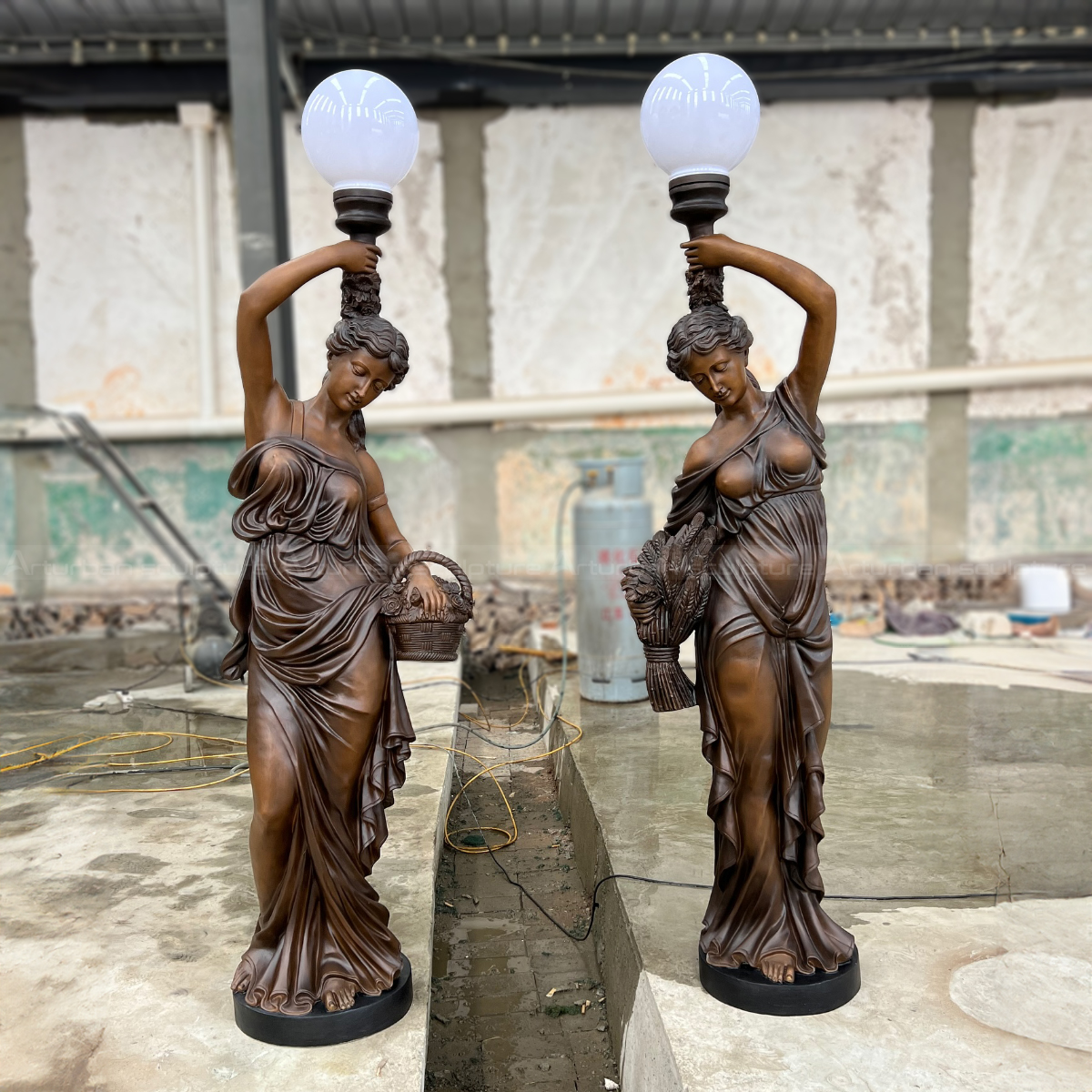 a pair of Lamp Statues each Woman holding a round globe light above their head and carrying a basket or a bundle of wheat