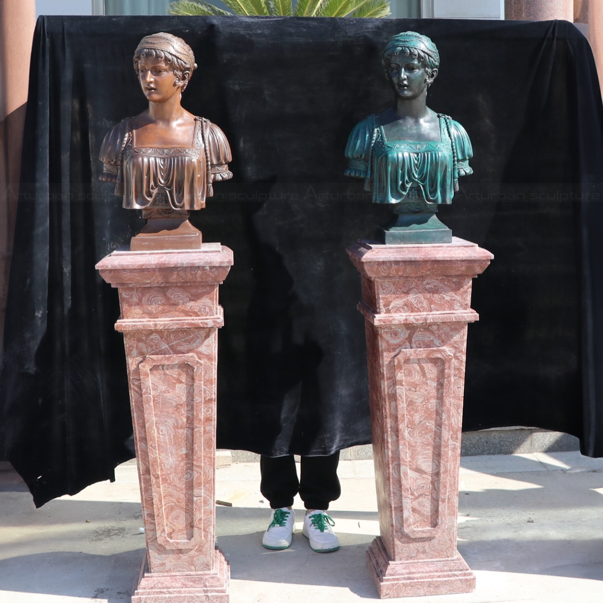 a pair of Roman Female Bust sculptures mounted on a tall red marble pedestal