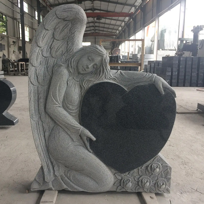 an angel gently leaning against and embracing a heart-shaped headstone statue