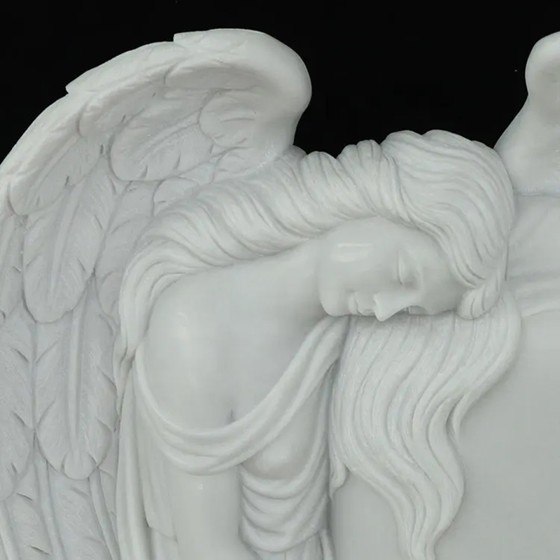 close up of white marble angel leaning on headstone
