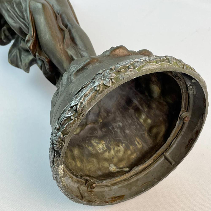 detailed close-up of bronze statue's base showing intricate floral decorations