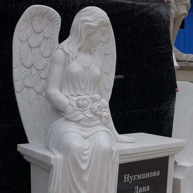 marble Angel Statue sitting on Headstone with a bunch of flowers