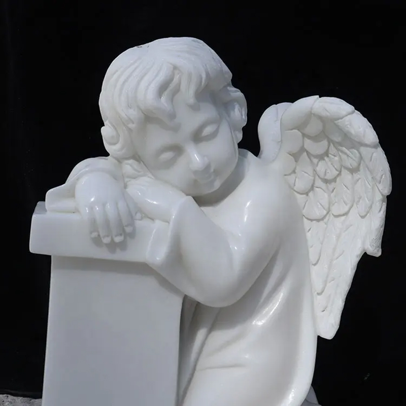 white marble Sleeping Cherub Statue resting its head on headstone