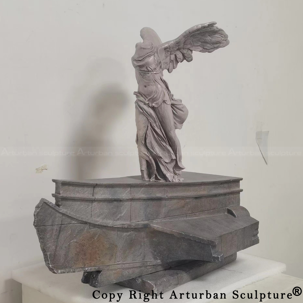 replica of the Winged Victory of Samothrace sculpture depicting a headless, winged female figure standing on the prow of an ancient warship