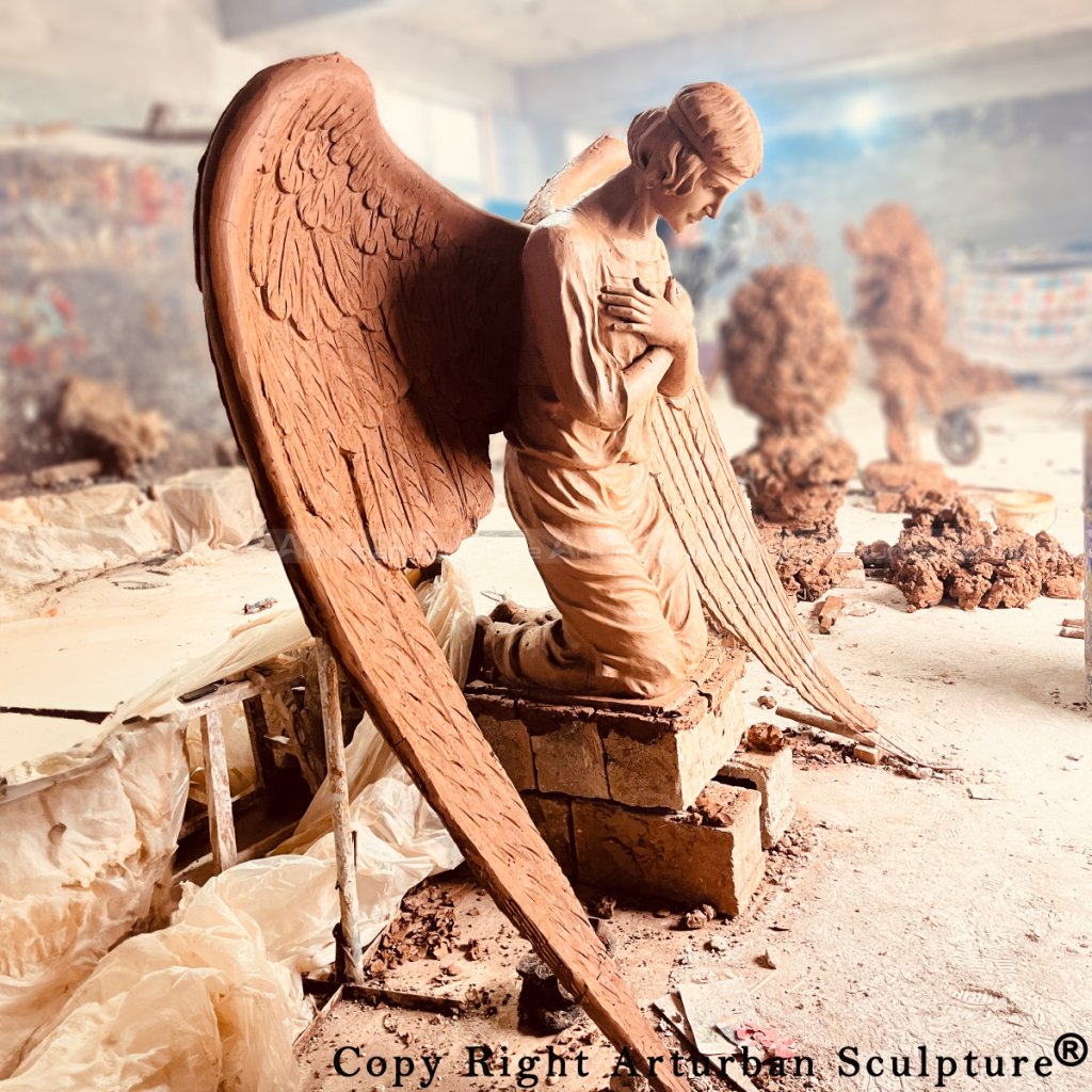Side view of the full-scale clay mold of a kneeling angel statue