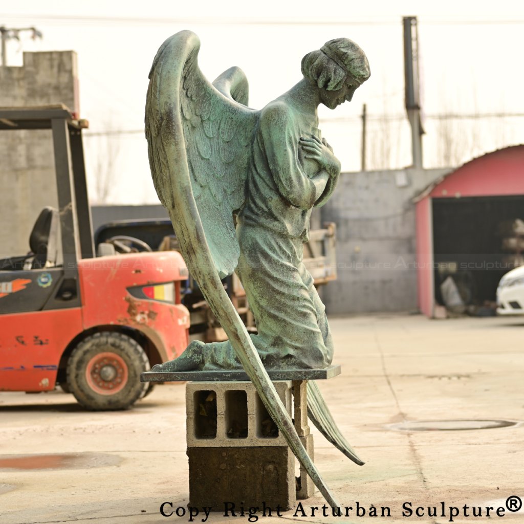 bronze kneeling angel statue with folded hands and bowed head