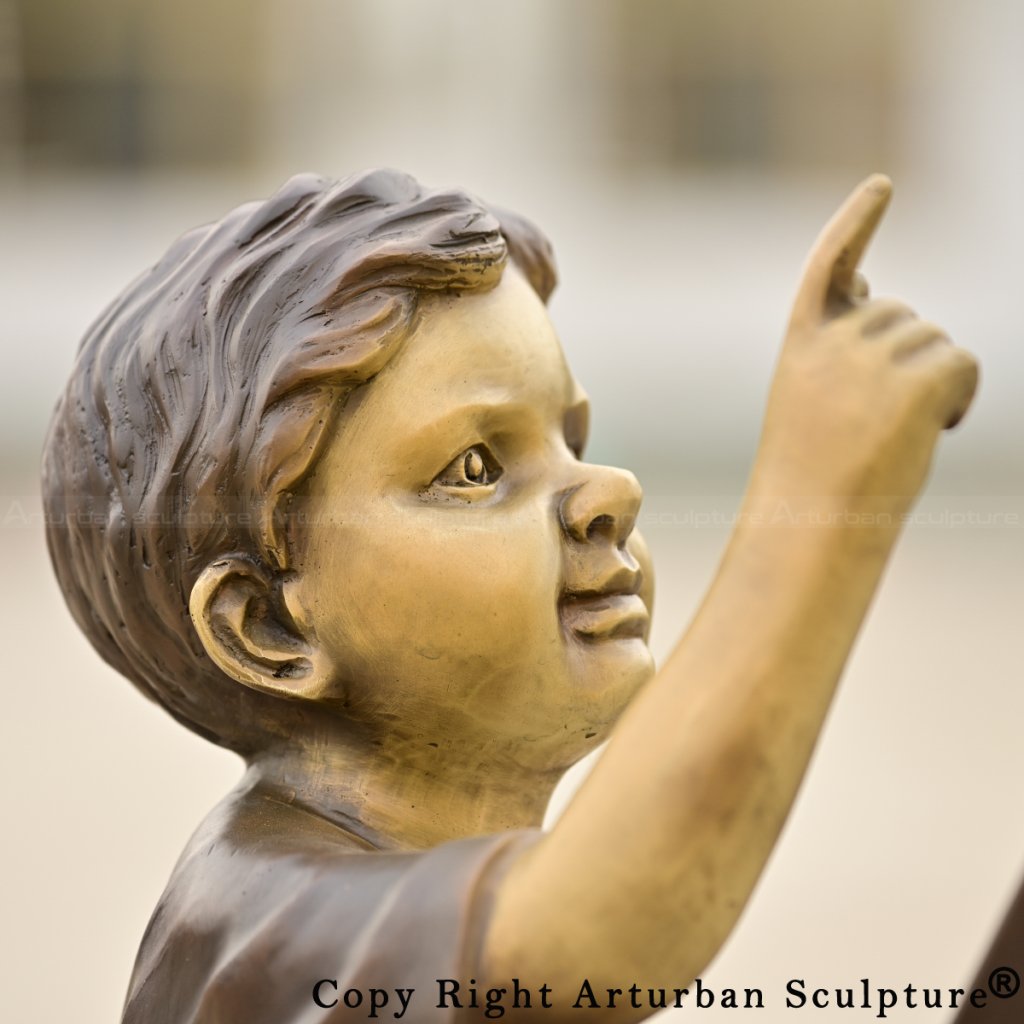 close up view of Children on Ladder bronze Sculpture depicting the boy pointing upward with one hand