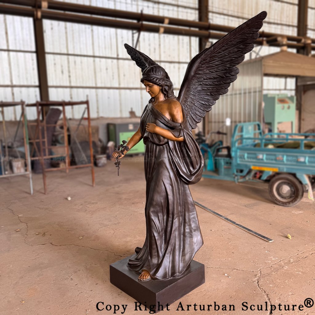 bronze memorial angel statue with outstretched wings, holding a rose