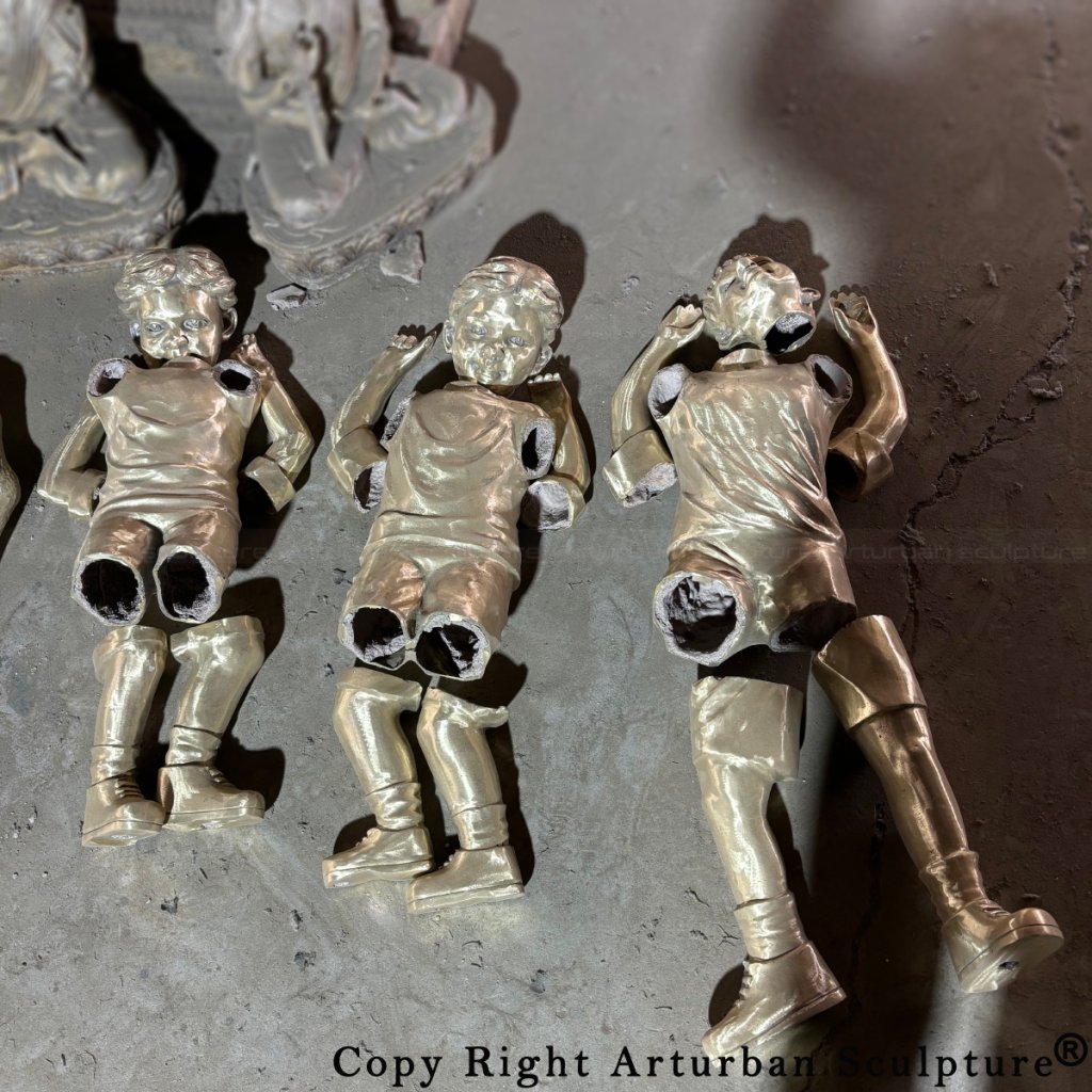 Separate cast bronze pieces of children figures laid out before welding and assembly