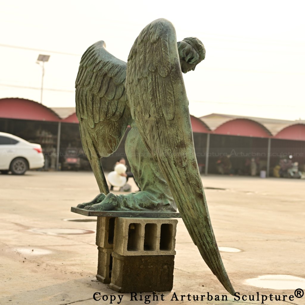 kneeling angel statue showing drooping wings and detailed texture