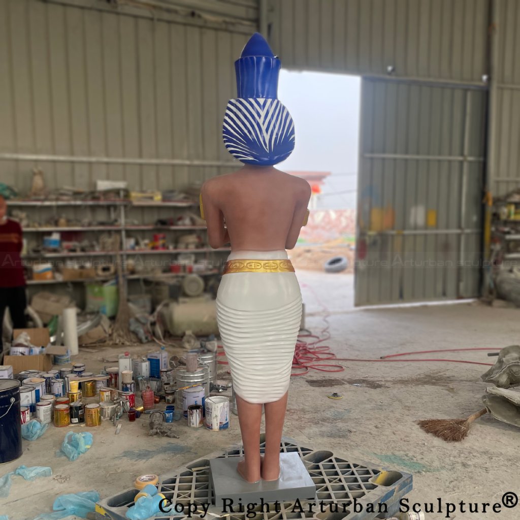 Rear view of the fiberglass pharaoh sculpture showing the blue and white striped headpiece and gold waistband