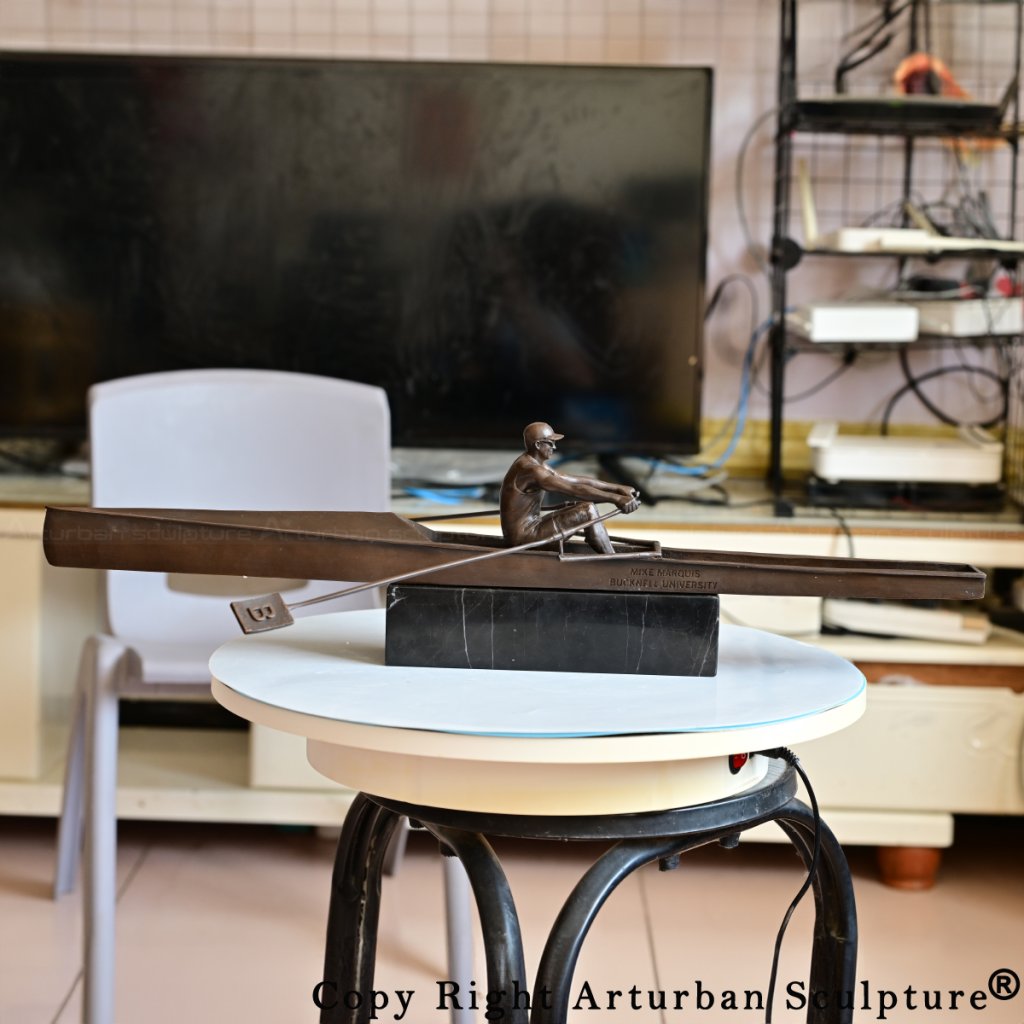Side view of bronze rowing sculpture on a round display table