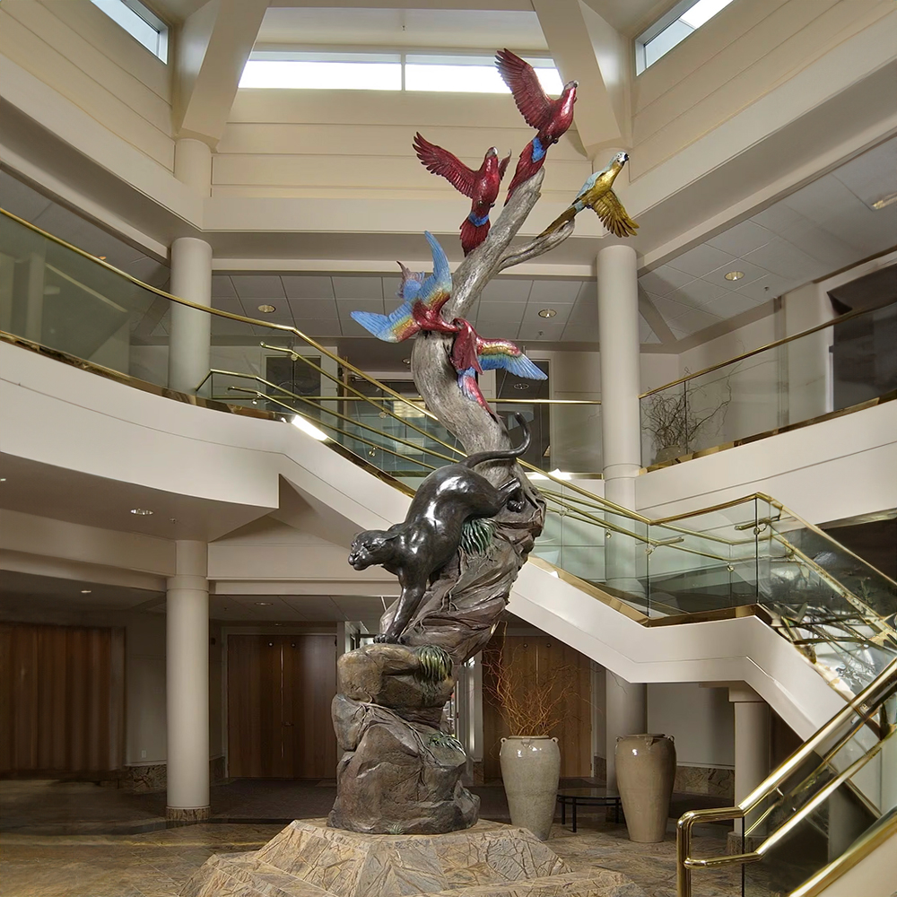 Bronze Jaguar and Macaws Sculpture showing a stealthy jaguar descending a twisting tree as colorful macaws soar upward