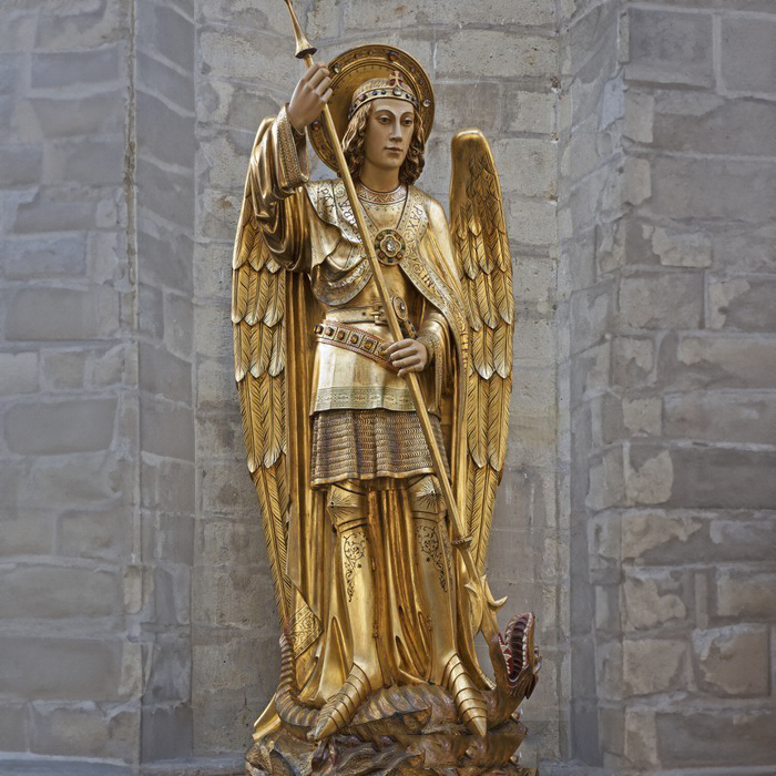Golden statue of Archangel Michael holding a spear and standing over a dragon