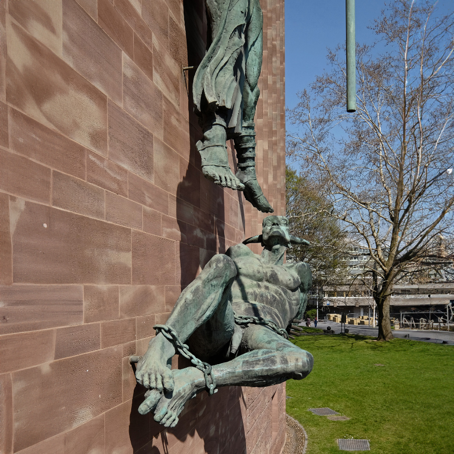 Low-angle view of Satan in chains beneath Archangel Michael sculpture at Coventry Cathedral