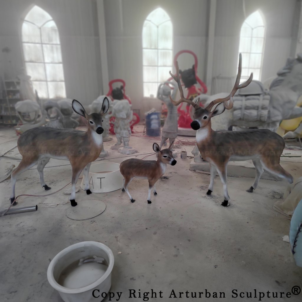 Whitetail Deer Family Sculpture in fiberglass showing a buck, doe, and fawn, displayed indoors during finishing stage