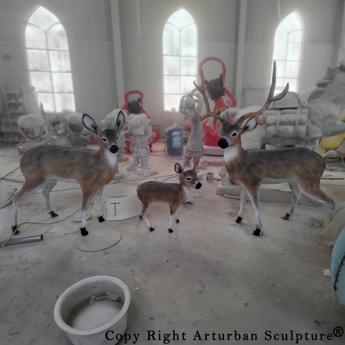 Whitetail Deer Family Sculpture in fiberglass showing a buck, doe, and fawn, displayed indoors during finishing stage