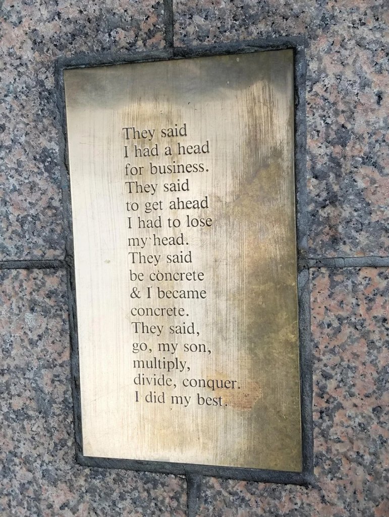 Bronze nameplate beneath the Corporate Head Sculpture displaying a poetic inscription