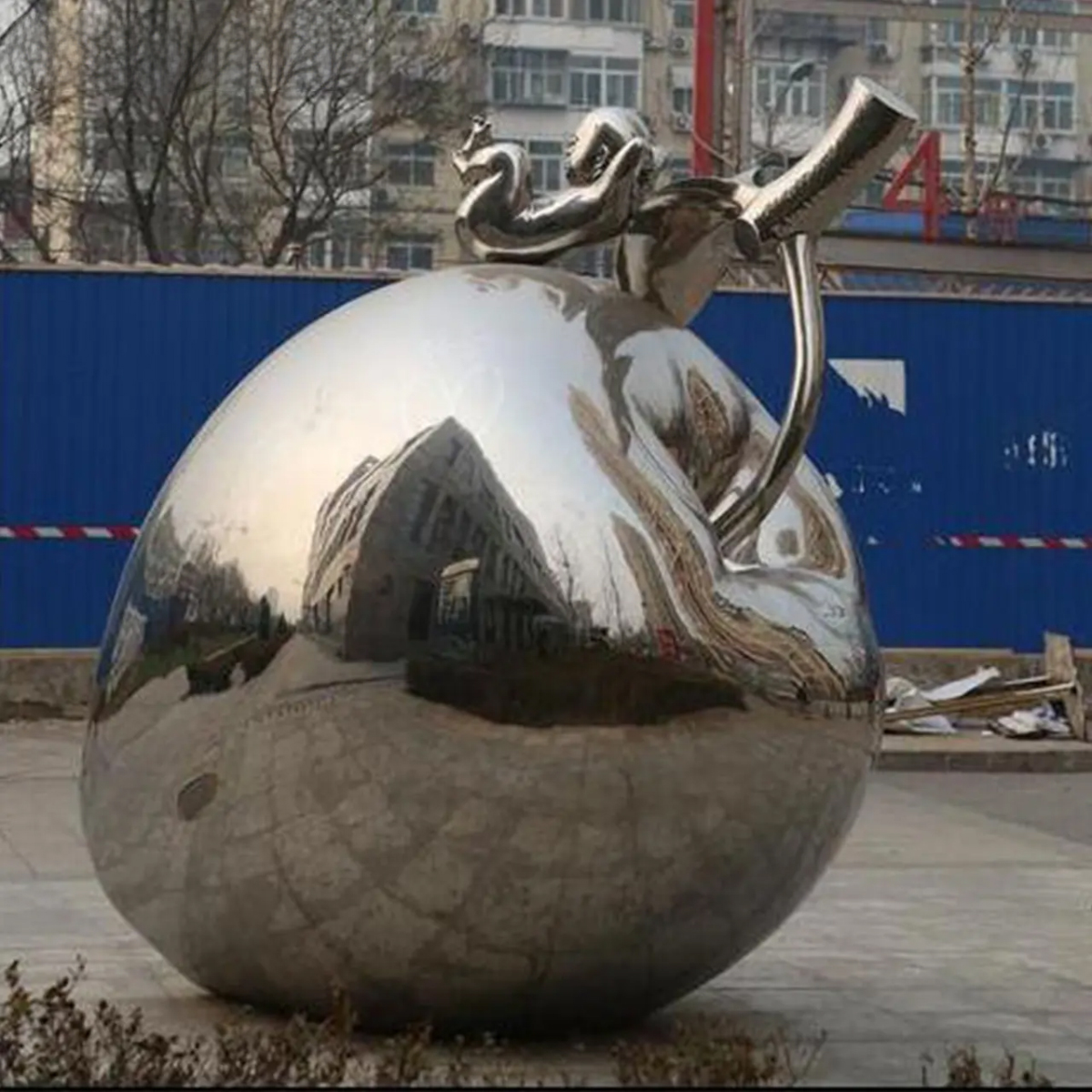 A stainless steel apple sculpture with a child figure on top