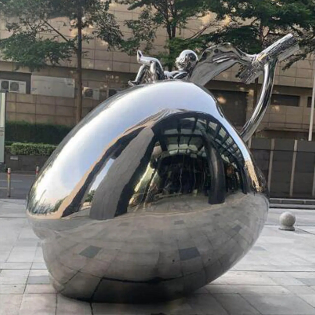 Apple-shaped stainless steel sculpture with a child figure