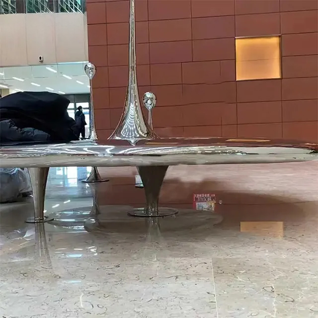 Close-up of a stainless steel Raindrop Statue with a tall droplet emerging from circular ripple design