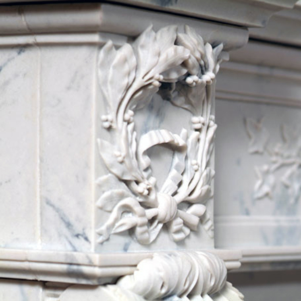 Detailed leaf and ribbon carving on side panel of French Marble Fireplace Surround in white marble