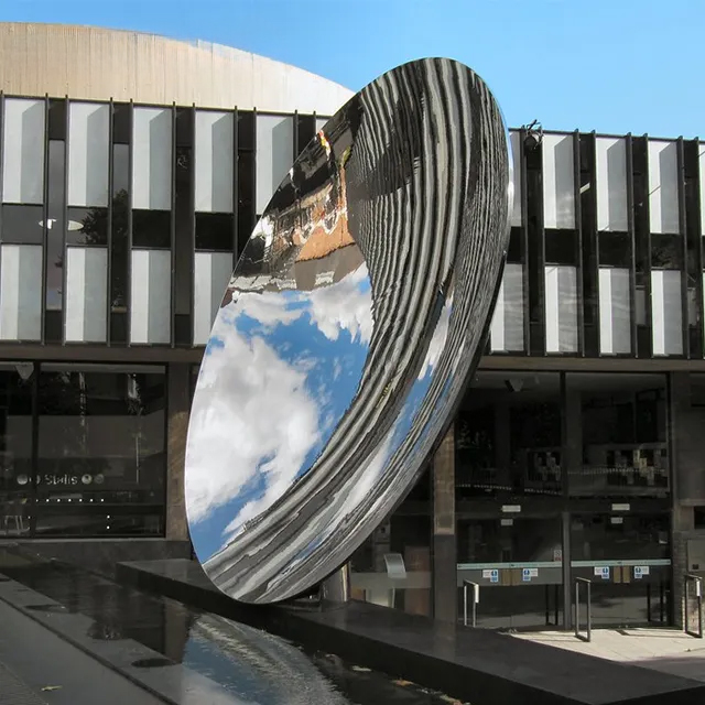 Large stainless steel Sky Mirror Sculpture capturing blue sky and clouds