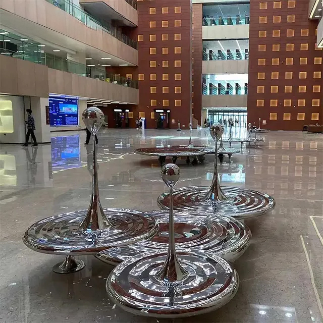 Mirror-polished stainless steel Raindrop Statues arranged on overlapping ripple discs
