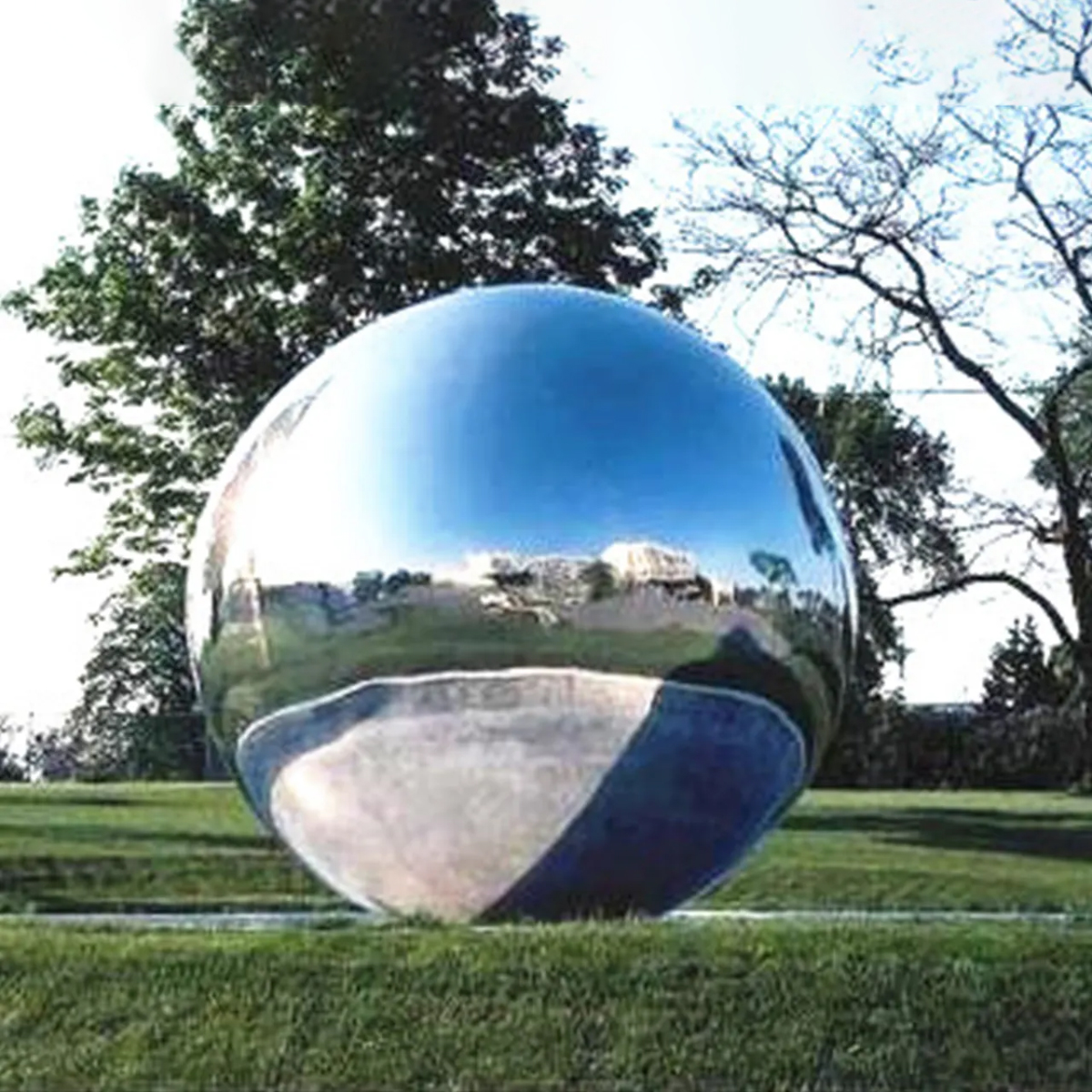 Large stainless steel ball sculpture partially submerged in a water fountain