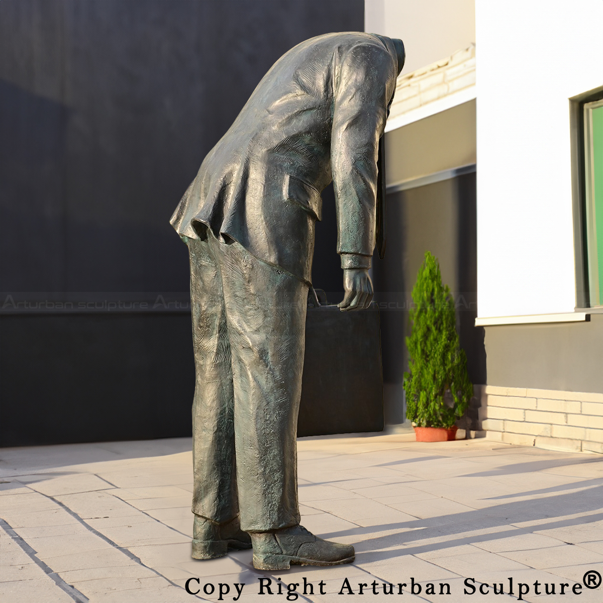 Side view of bronze Corporate Head Statue with headless businessman figure leaning