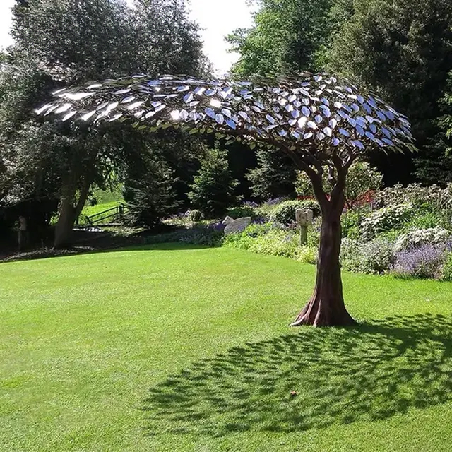 Stainless steel tree garden sculpture by Mark Reed with reflective metal leaves and forged trunk