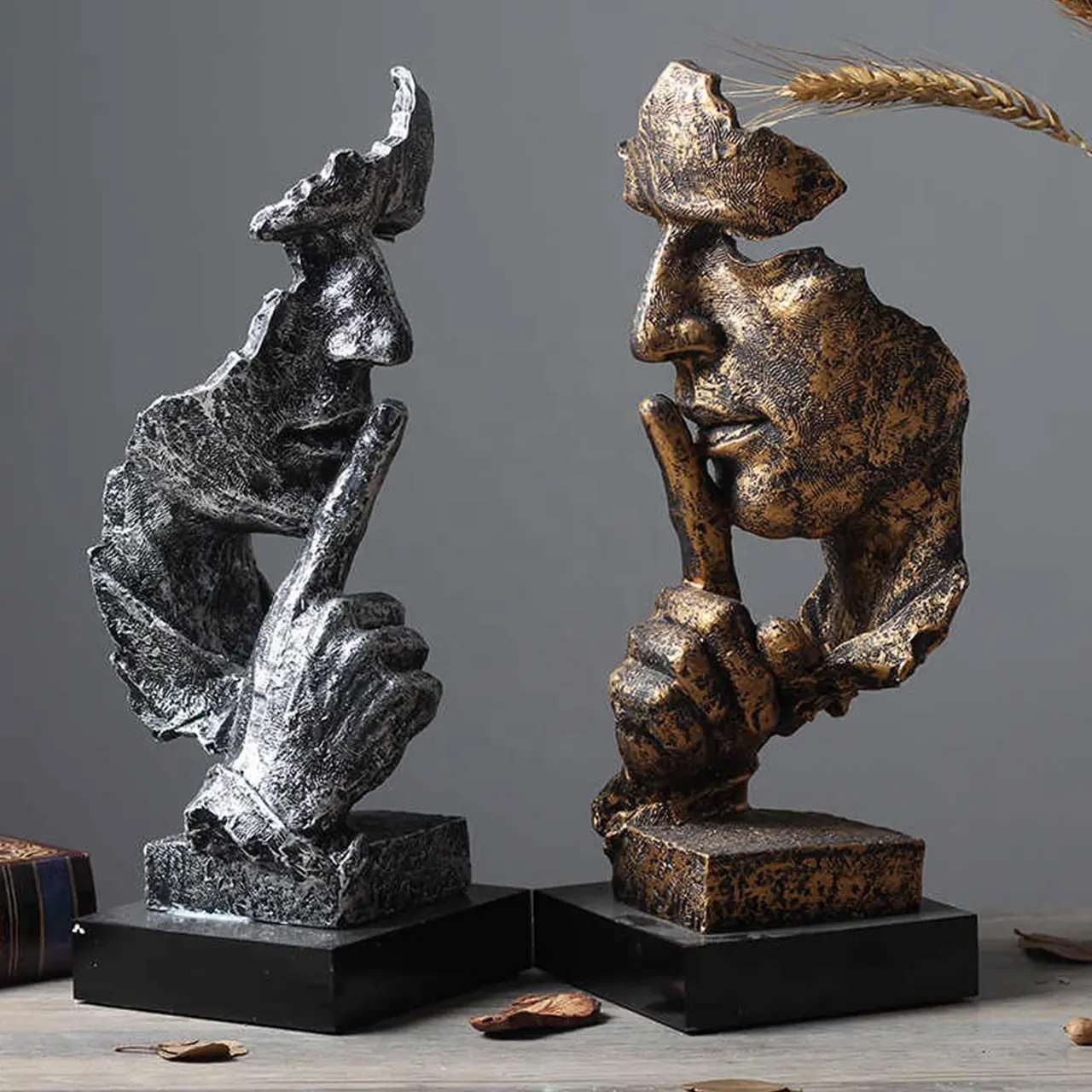 Two Statue of Silence sculptures in bronze and silver with shushing gestures