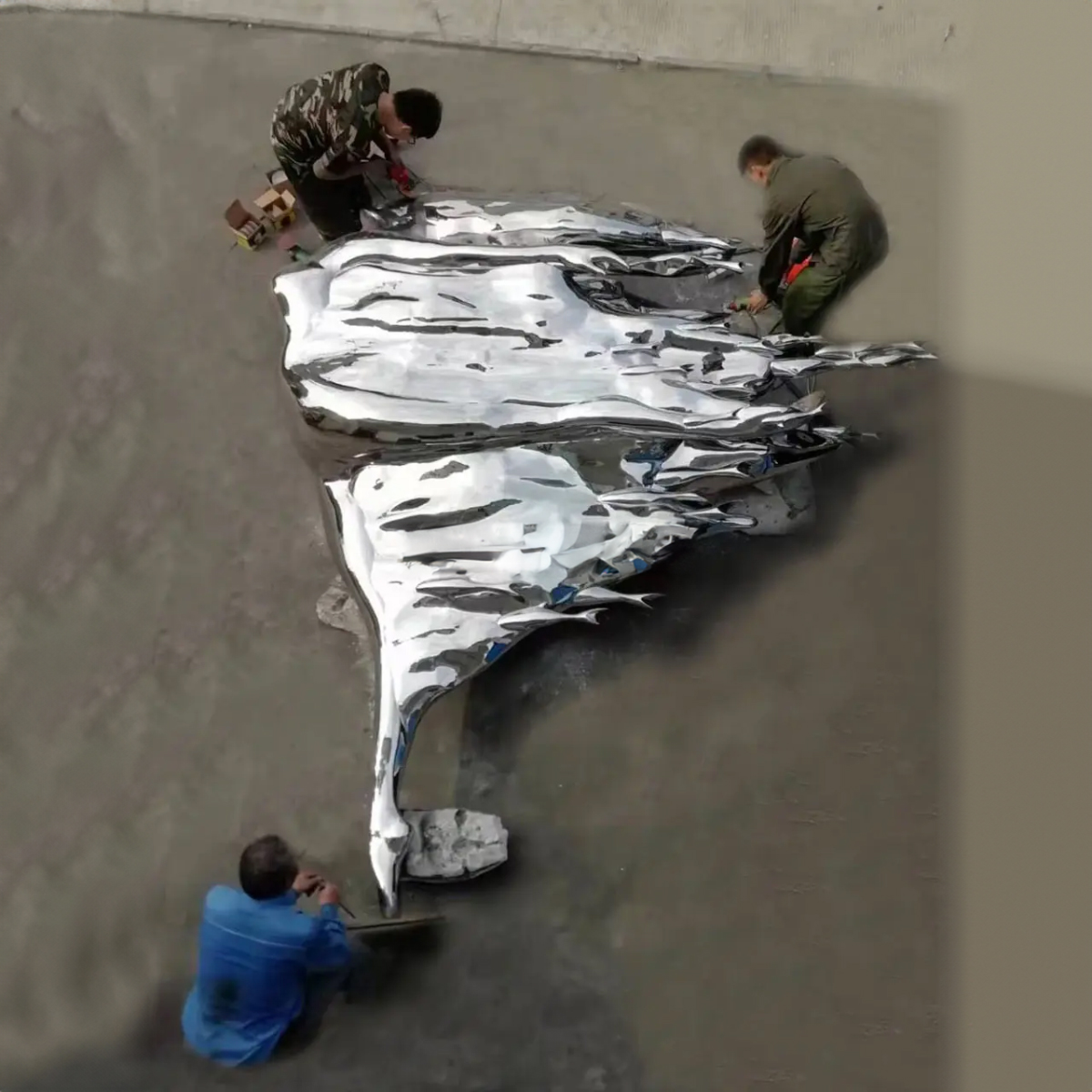 Workers installing a stainless steel Woman in the Wind Statue