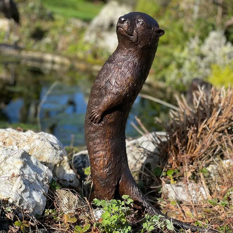 bronze Otter Garden Sculpture beside pond