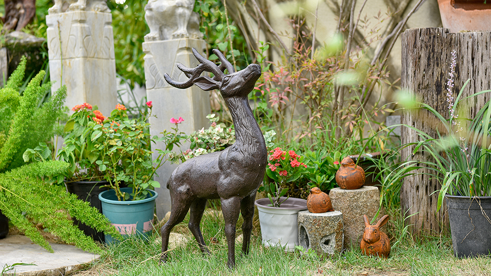 4.3.2-Small-bronze-deer-sculpture-for-yard-placed-in-a-garden-with-flowers-and-plants