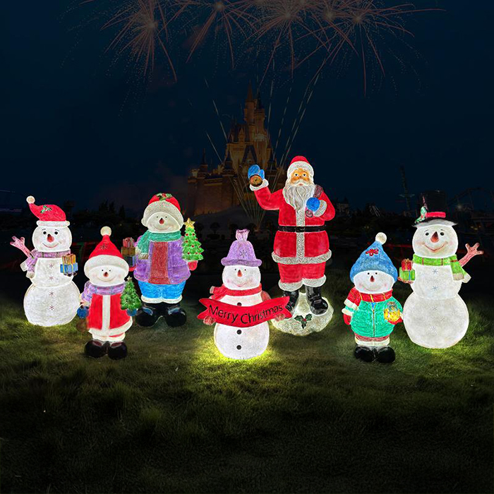 A group of Christmas sculptures featuring Santa Claus and several snowmen, glowing at night