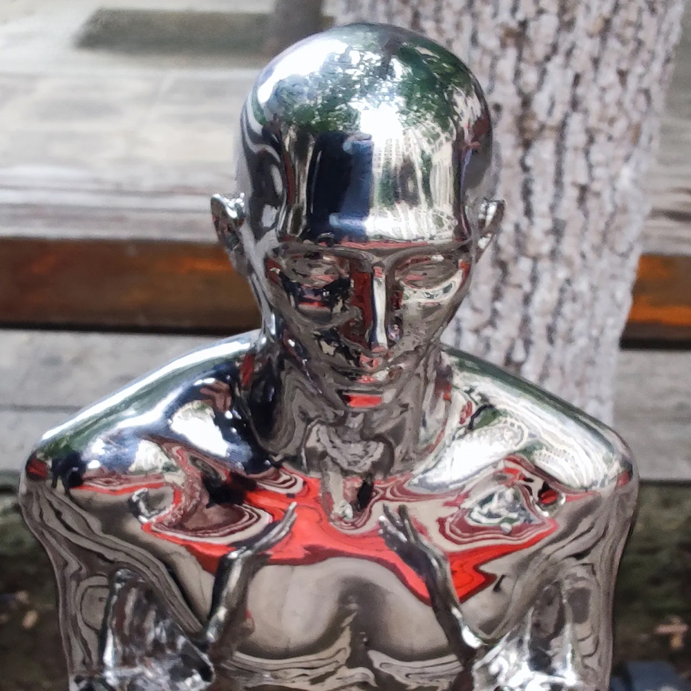 Close-up of the head and torso of a polished stainless steel man sculpture