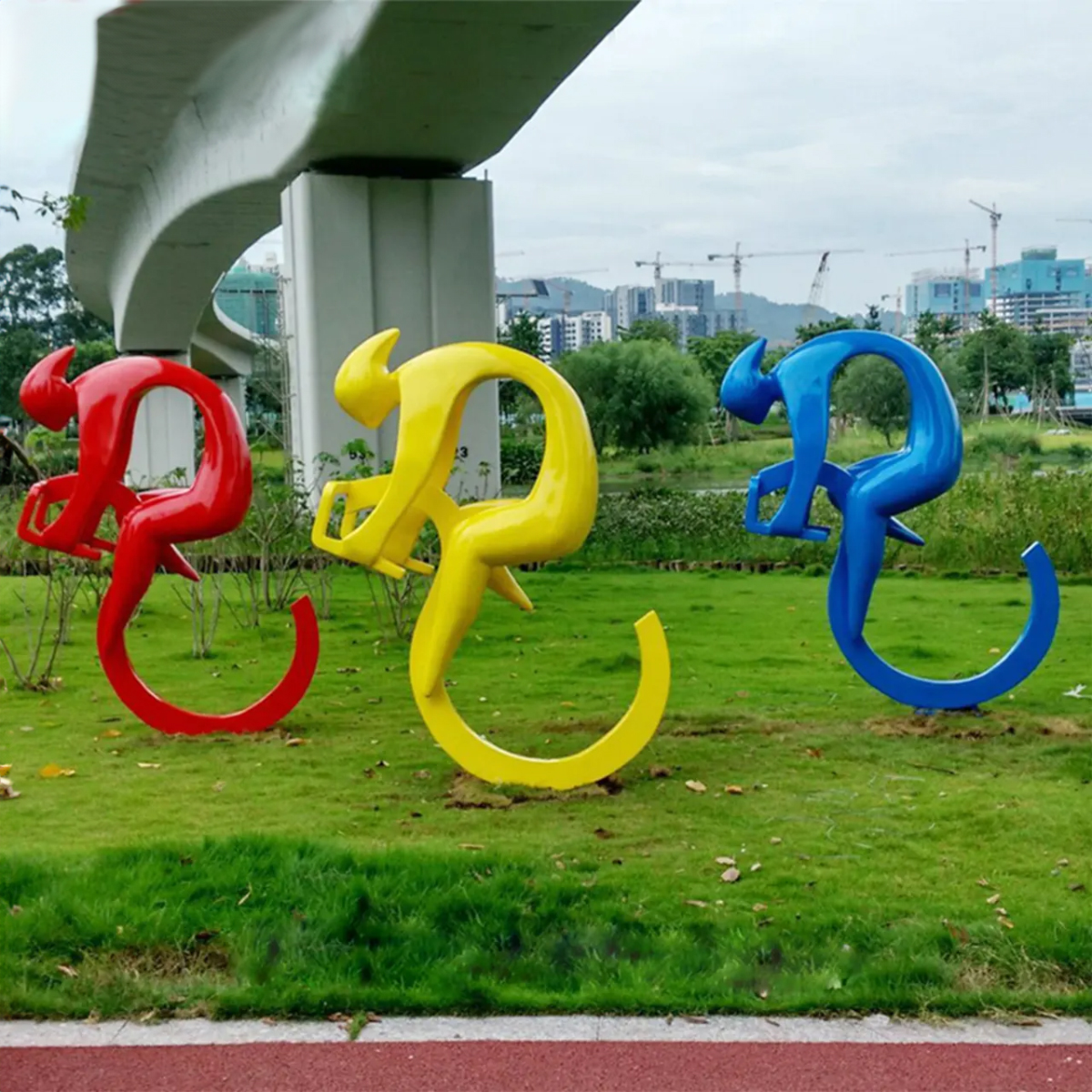 Cycling Art Sculpture with three stainless steel figures painted in red, yellow, and blue