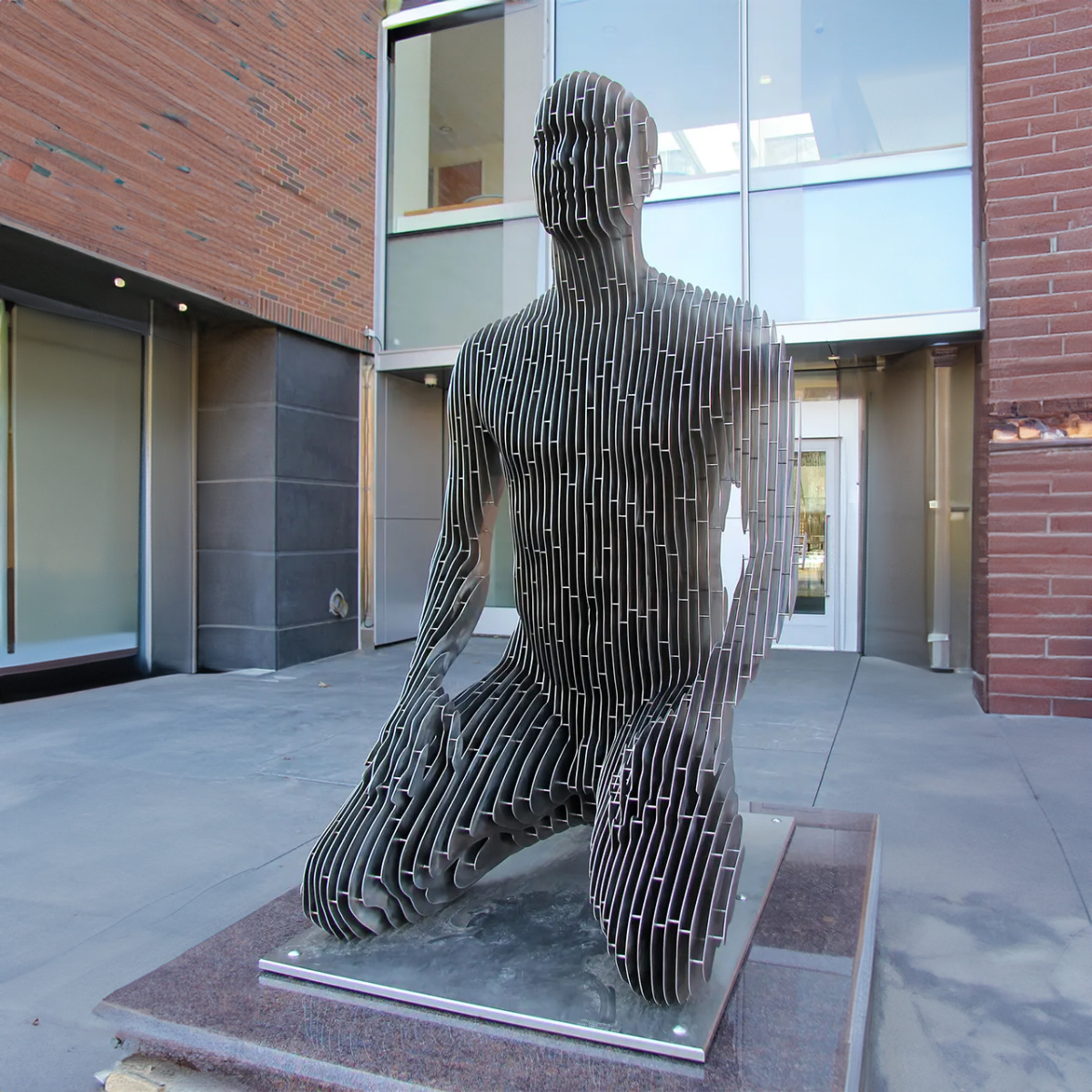 Man Kneeling Statue in stainless steel with layered cut design