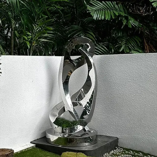Modern metal statue in stainless steel featuring dual oval loops with tapered tails extending toward the center