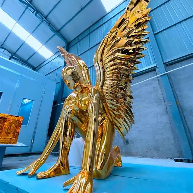 Outdoor gold angel sculpture with stainless steel wings in kneeling pose