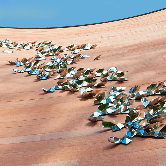 Stainless Steel Wall Sculpture of abstract leaf shapes on curved red brick wall