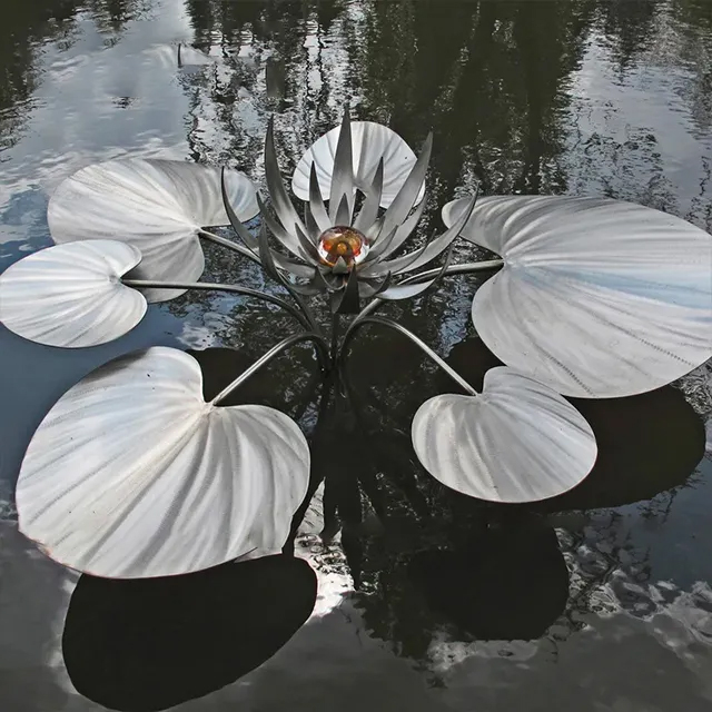 Stainless steel metal garden flower sculpture of a floating water lily with wide leaves and amber centerpiece