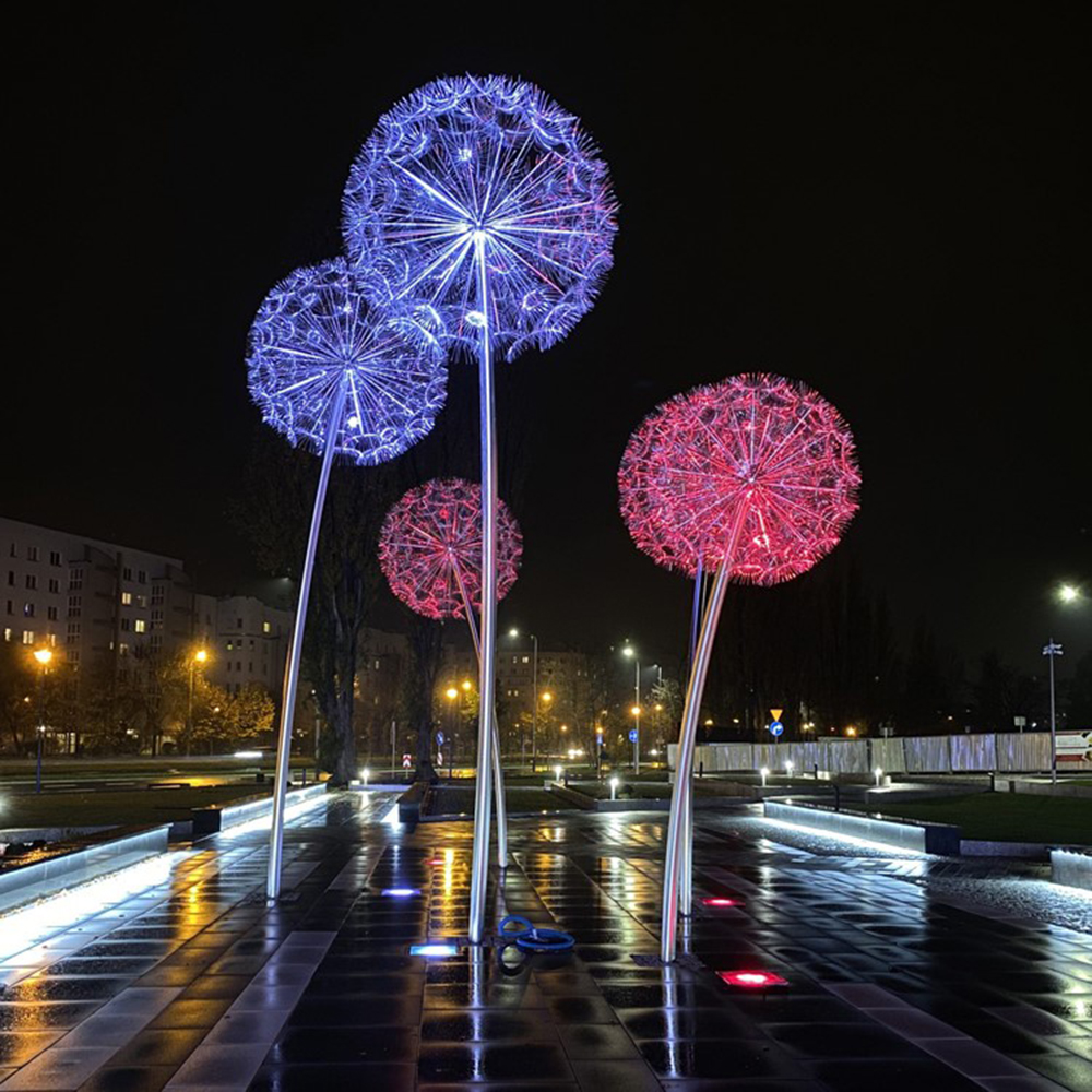Illuminated stainless steel garden dandelion sculpture glowing in blue and red lights