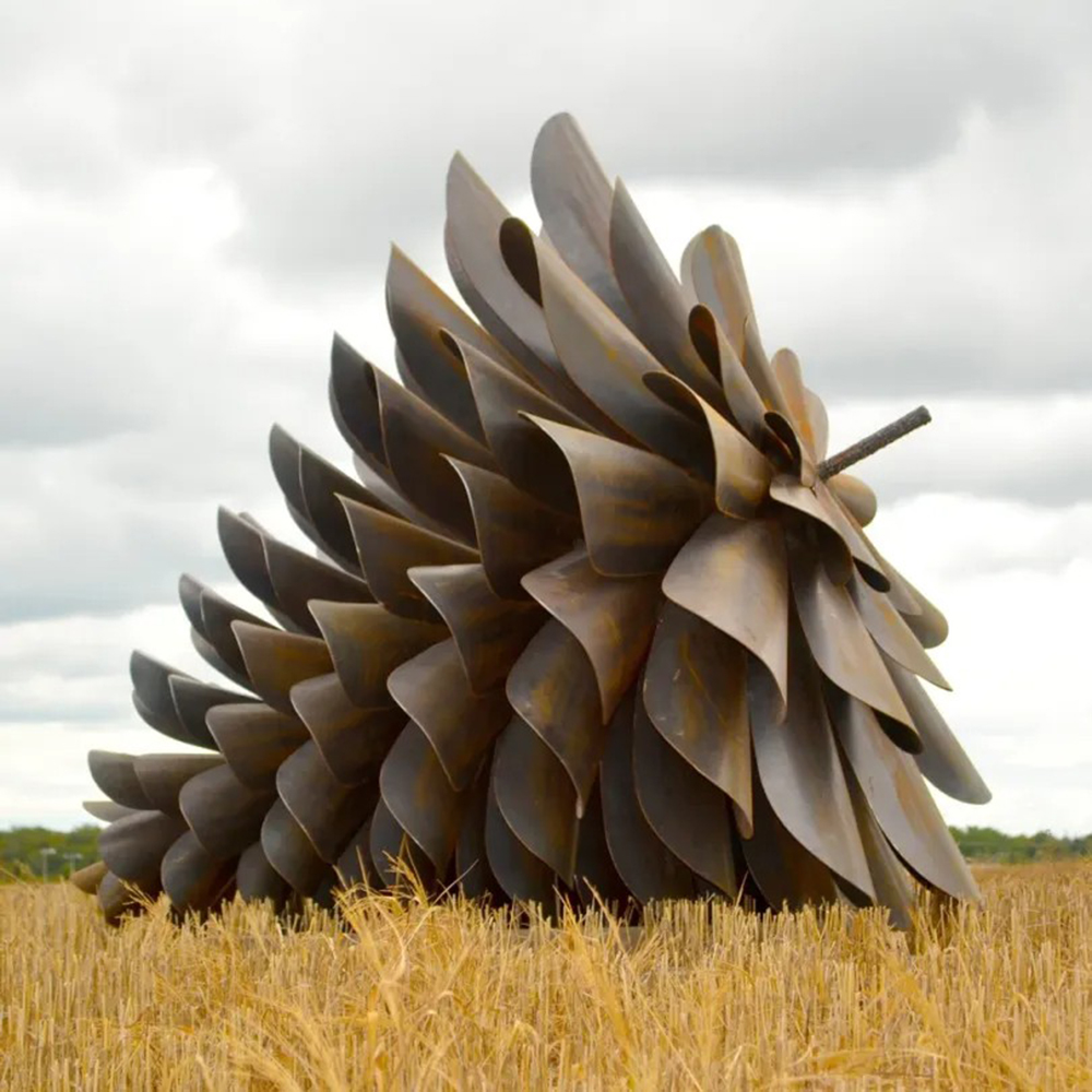 Large metal pine cone garden sculpture in field
