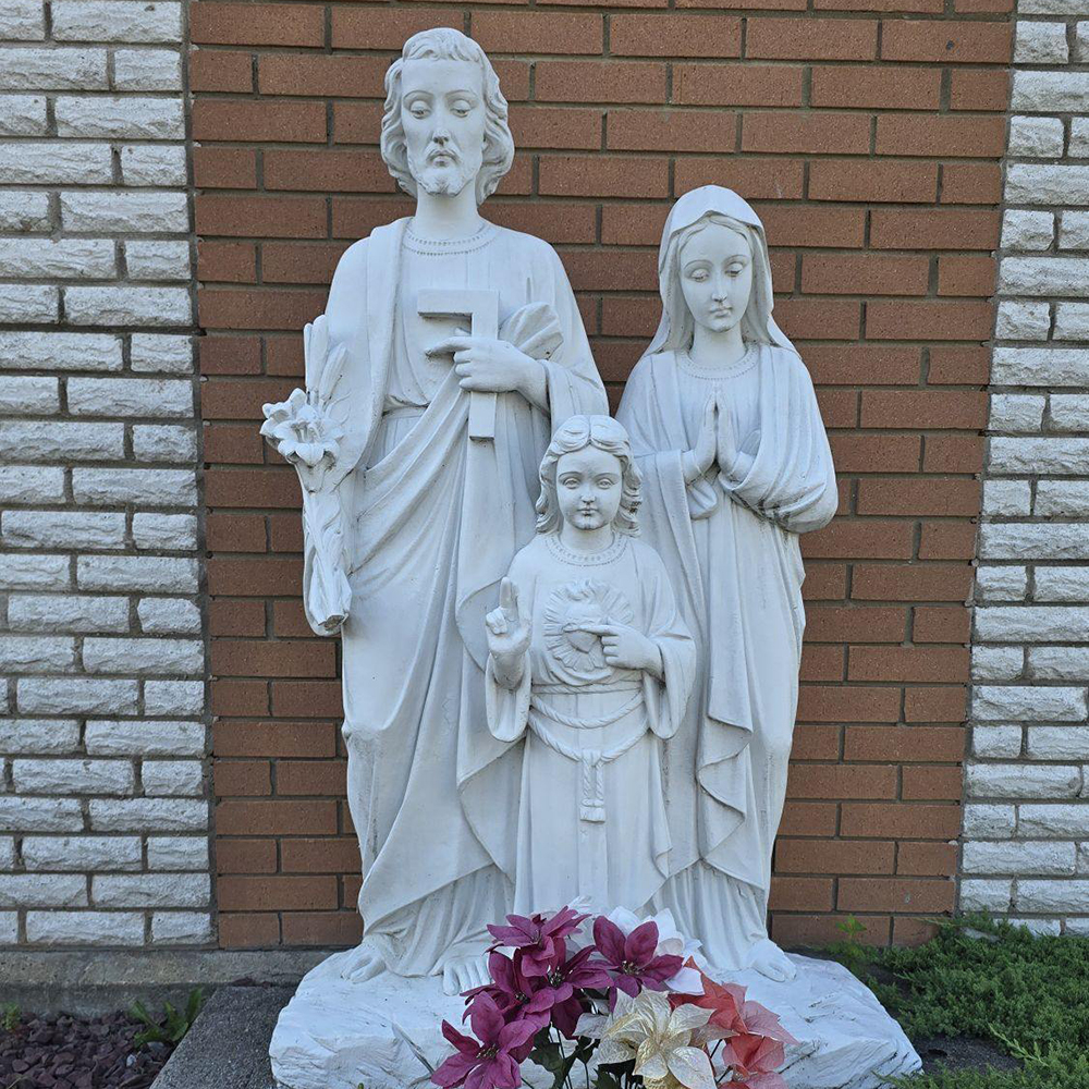 White stone Holy Family statue by church wall