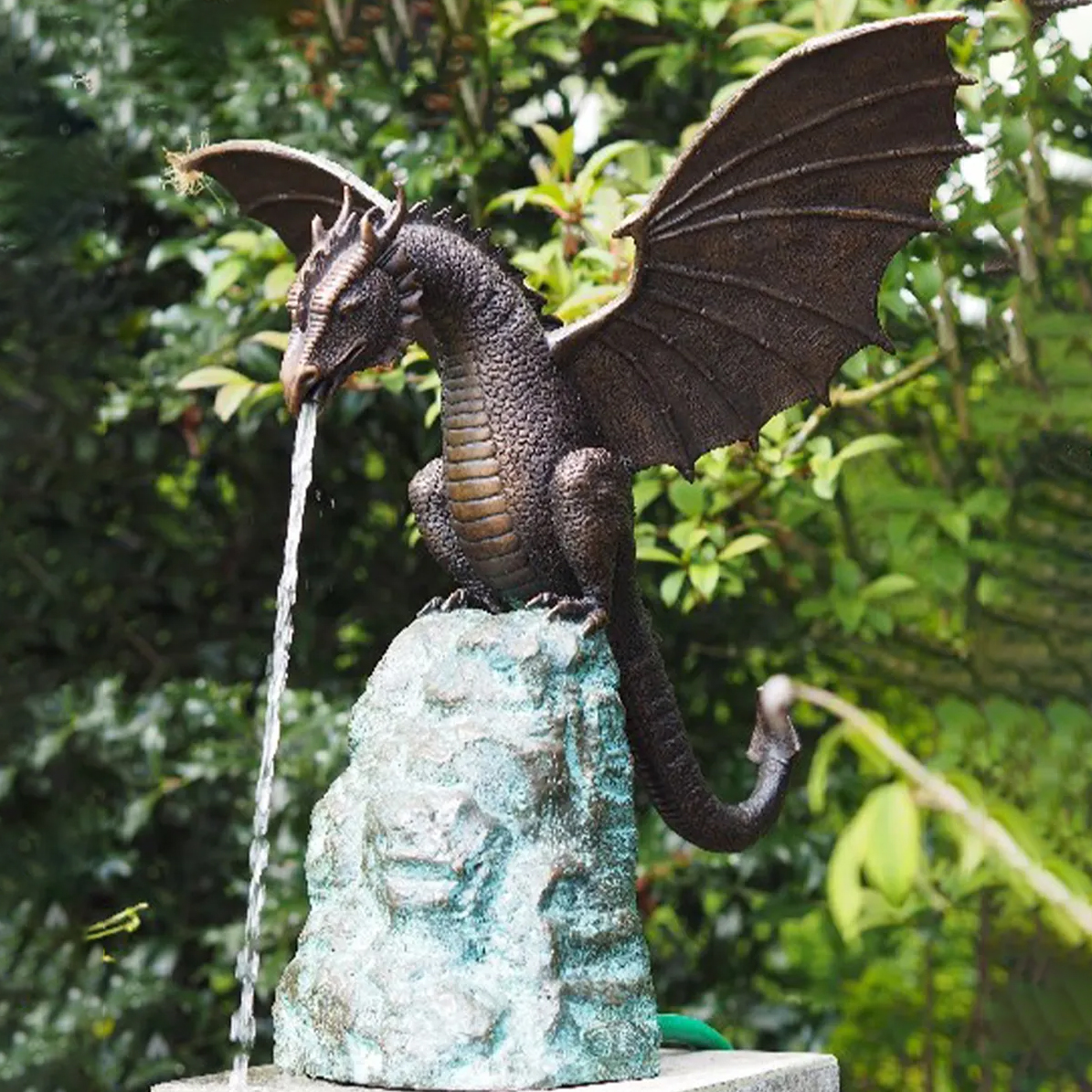 This group of dragon sculptures is modeled after pterosaurs from Western fantasy culture, featuring typical characteristics such as a long neck, wings, scales, and a coiled tail. The dragon's head has a sharp outline, with horn-like protrusions on the forehead and back of the neck. The wings are fully extended to the sides, with the wing membranes separated by clear skeletal lines. Some sculptures perch on rocks, leaning forward with their heads protruding downwards; others are coiled on spherical or square bases, their claws firmly gripping the support, presenting a posture of guarding territory or preparing for takeoff. The sculptures are made of bronze, with surfaces mostly treated with dark brown, black, or locally bluish-green patina, making the scales, wing membranes, and rock textures more clearly defined. Some of the Dragon Pond Spitters have water spouts inside the dragon's mouth; when connected to a water pump, they can spray a continuous stream of water downwards, suitable for integration with ponds, fountains, water basins, or garden water features. The sculptures can serve as functional water features or as independent outdoor fantasy decorations, suitable for placement in private gardens, courtyard ponds, castle-themed landscapes, resorts, theme parks, or commercial water features.